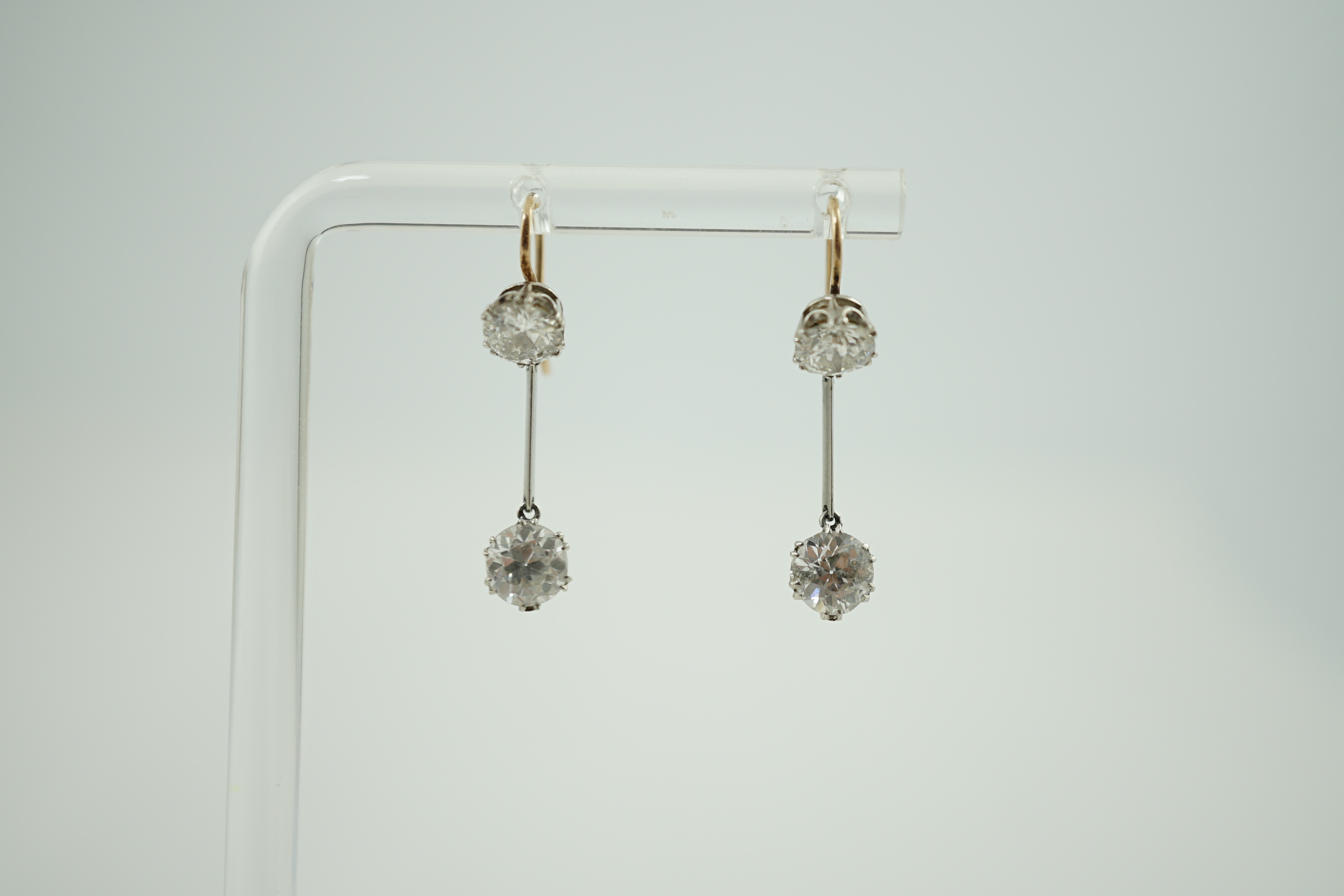 A pair of gold and graduated two stone diamond set drop earrings